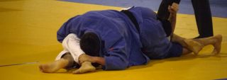 (Above) A triangle (sankaku jime) hold and strangle at the 2010 Belgian Open tournament. (Background) A Japanese player counters his Kazakh opponent with a pick-up throw (te-guruma) at the 2011 World Judo Championships in Paris.
